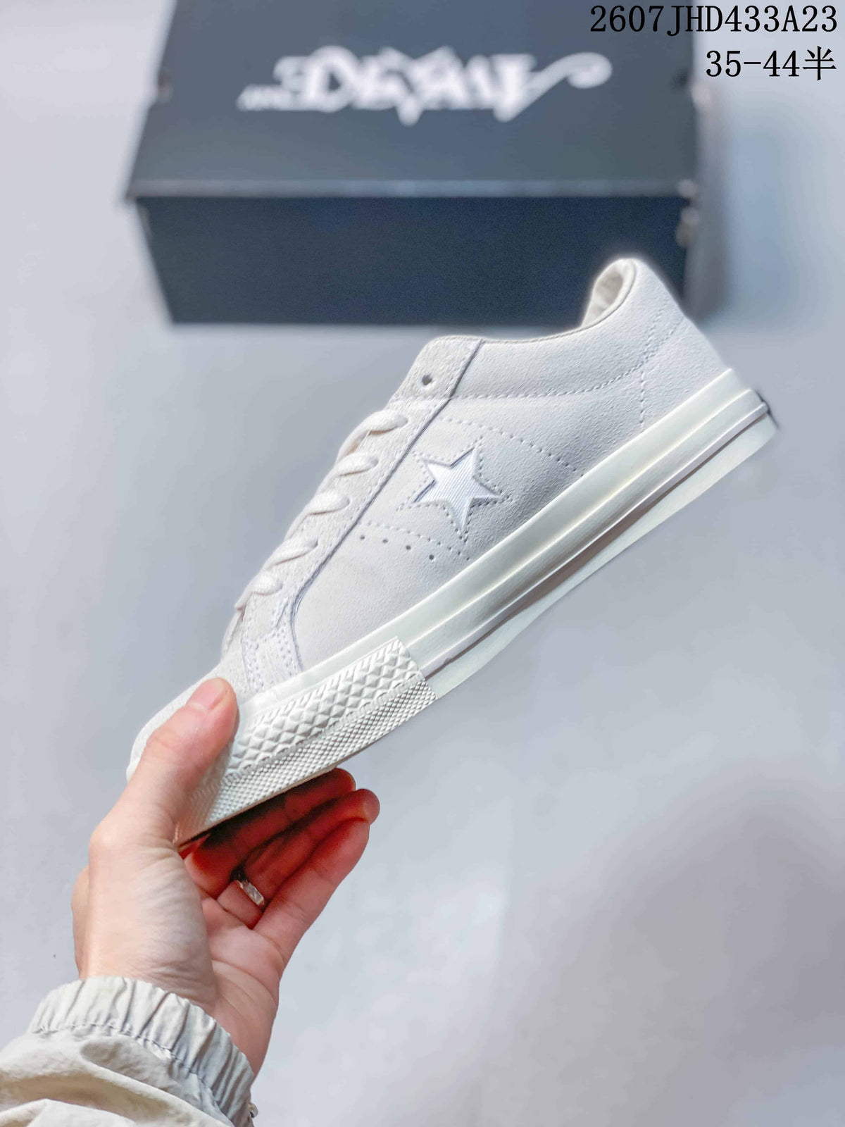 Side profile of the white low-top sneaker showing the star detail, stitched panels, laces, and rubber outsole.
