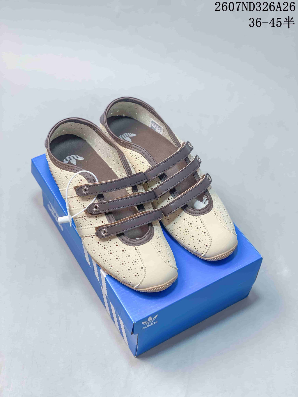 Pair of cream and brown Adidas Originals Mary Jane trainers displayed on a blue shoebox.