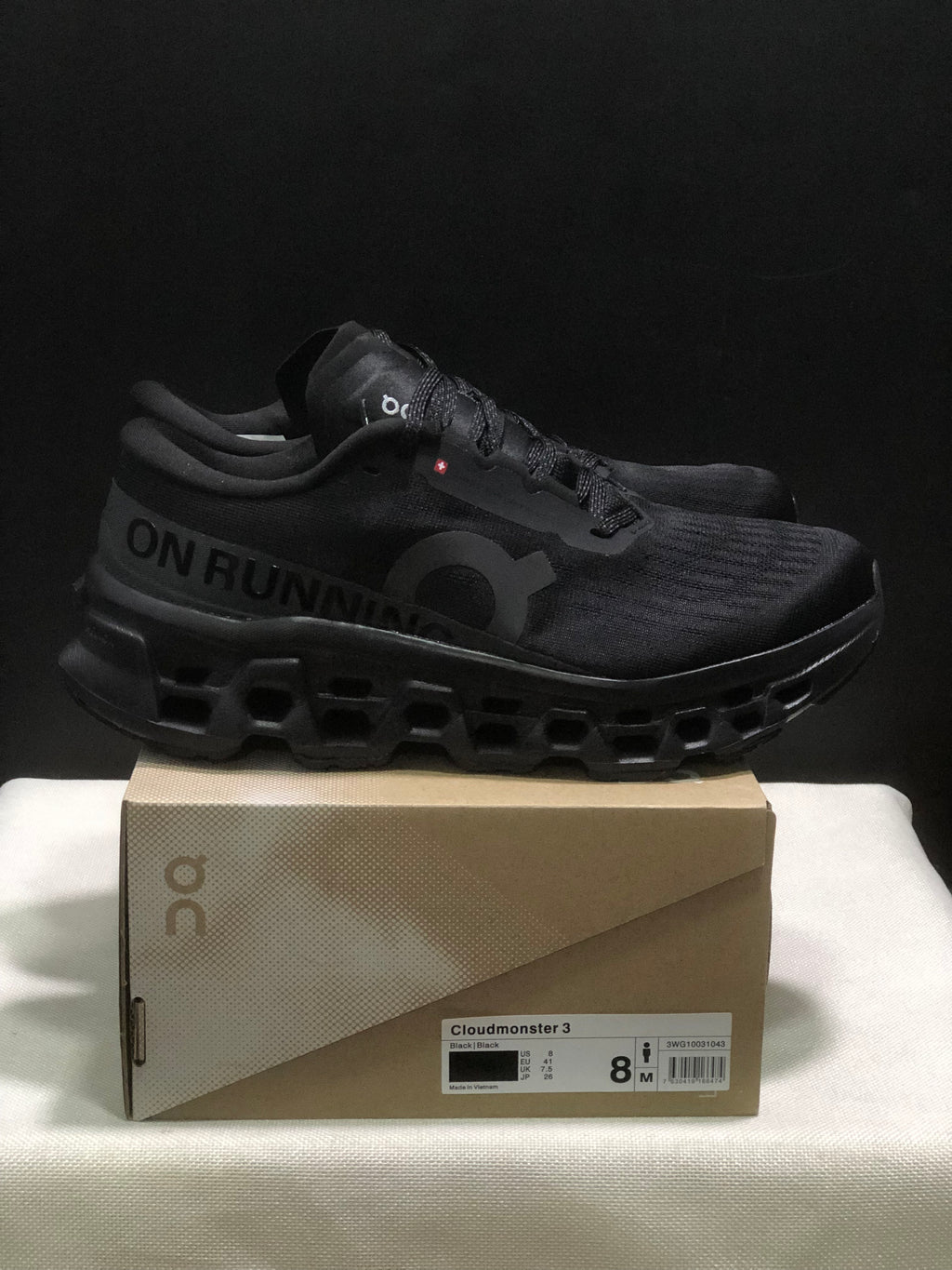 Side view of black On Cloudmonster 3 sneakers with visible branding and sculpted outsole.