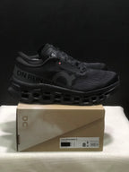 Side view of black On Cloudmonster 3 sneakers with visible branding and sculpted outsole.