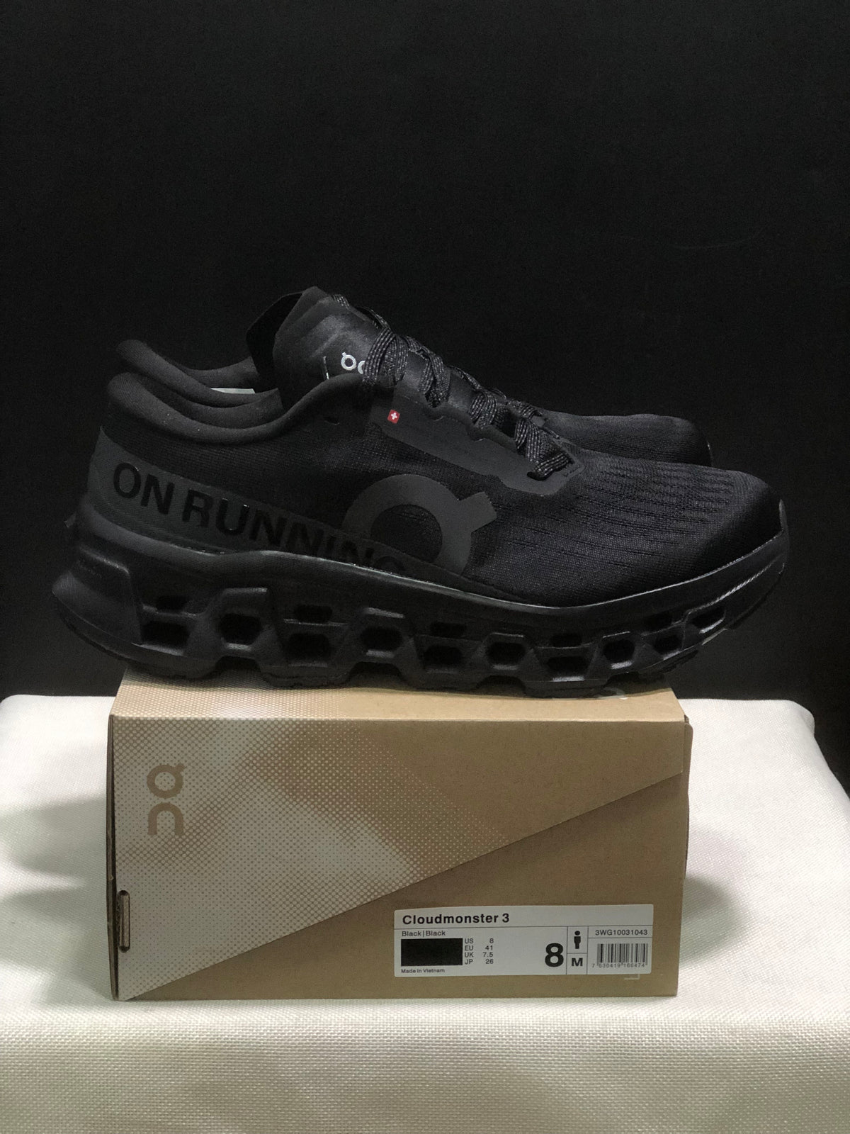 Side view of black On Cloudmonster 3 sneakers with visible branding and sculpted outsole.