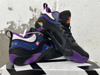Pair of black and purple Jordan basketball shoes shown at an angle, highlighting the patterned sides and sculpted soles.