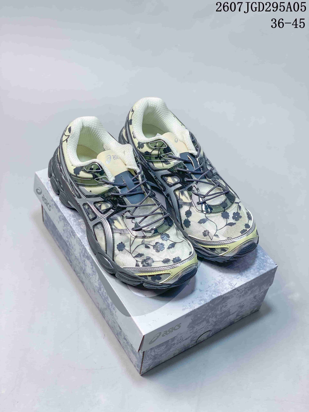 Pair of ASICS Gel-Cumulus 16 sneakers in a light green floral pattern with charcoal details, displayed on a shoebox; style code 2607JGD295A05 and size range 36–45 are visible.