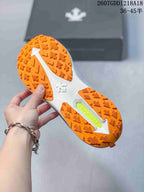 Close view of the orange lugged outsole with a white central section and a bright green insert.