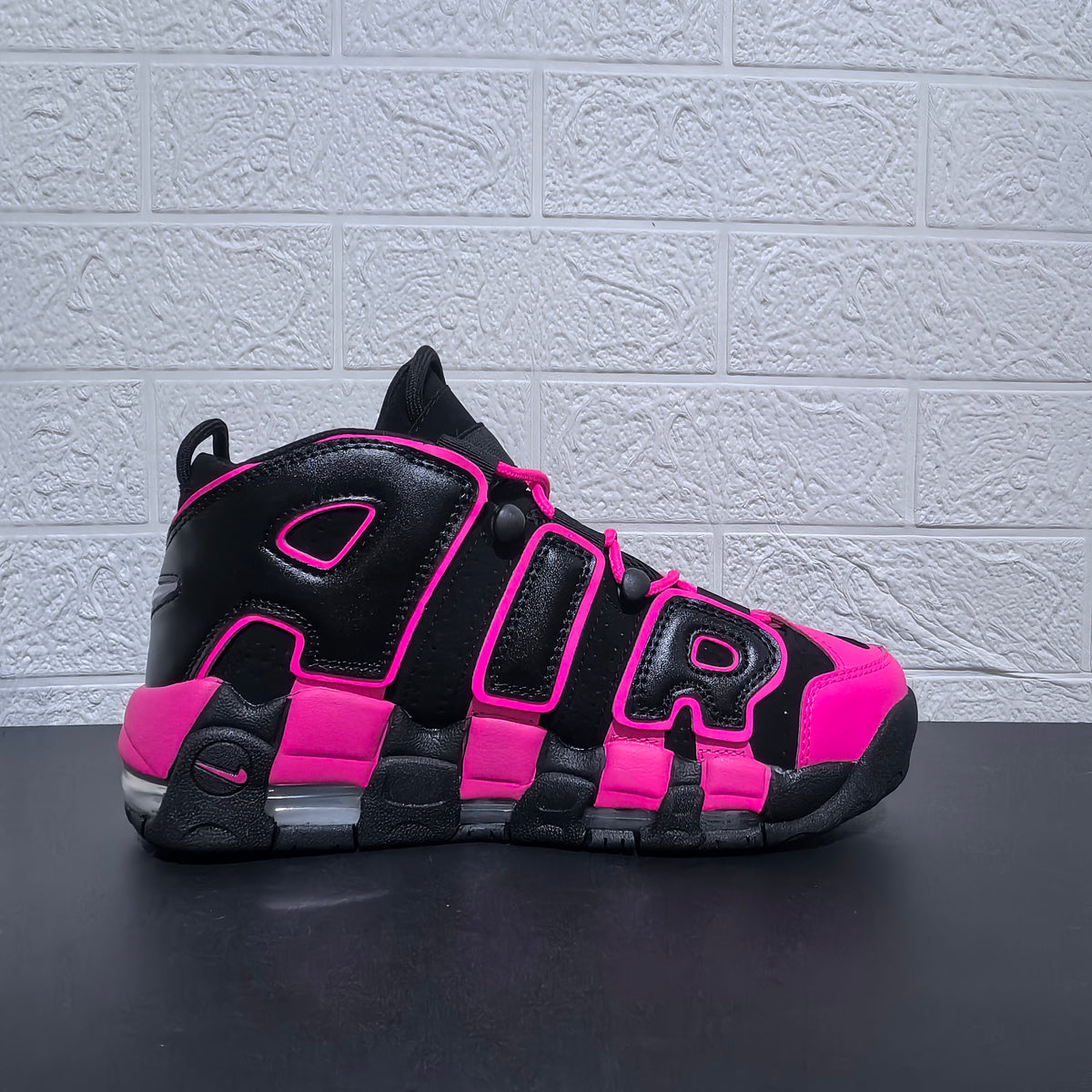 Side profile of a black and pink Nike Air More Uptempo sneaker