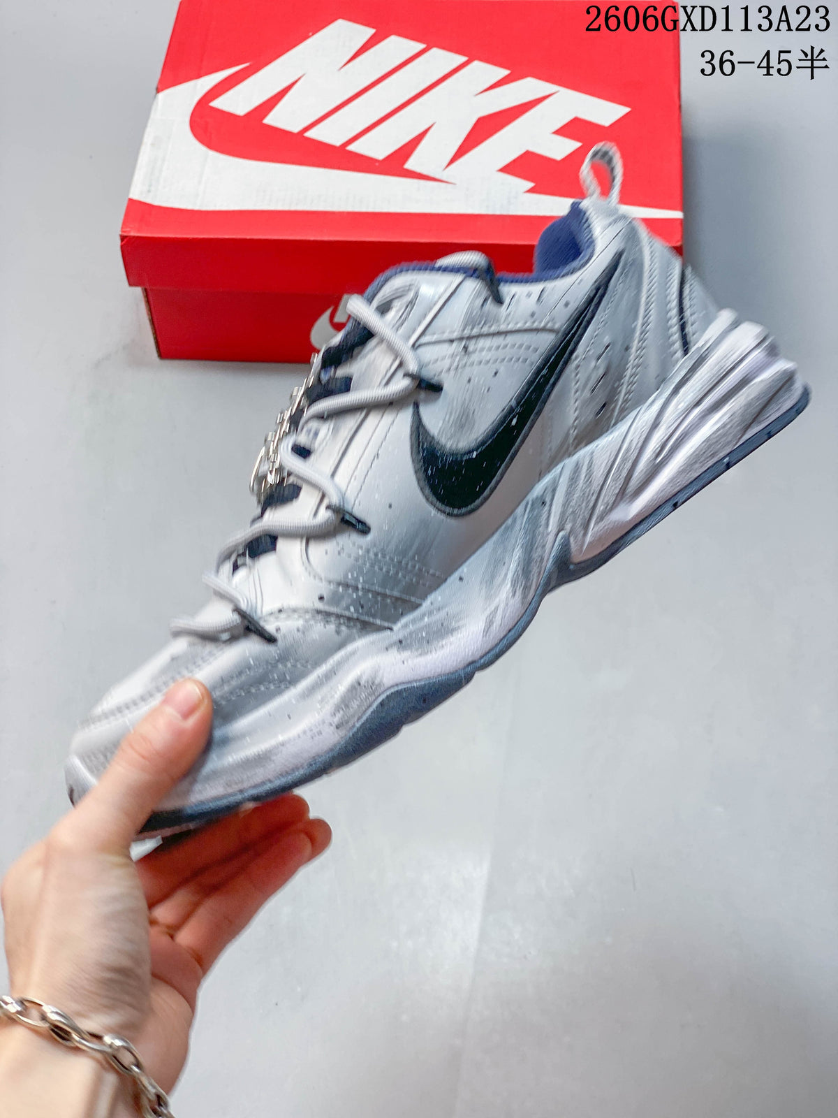 Side view of the silver sneaker with a dark Swoosh, layered panels, and chunky sole.