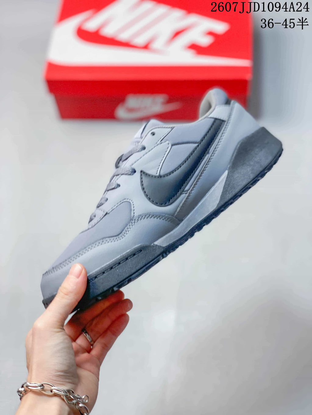 Side profile of the gray sneaker showing layered panels, dark Swoosh branding, and the thick outsole.