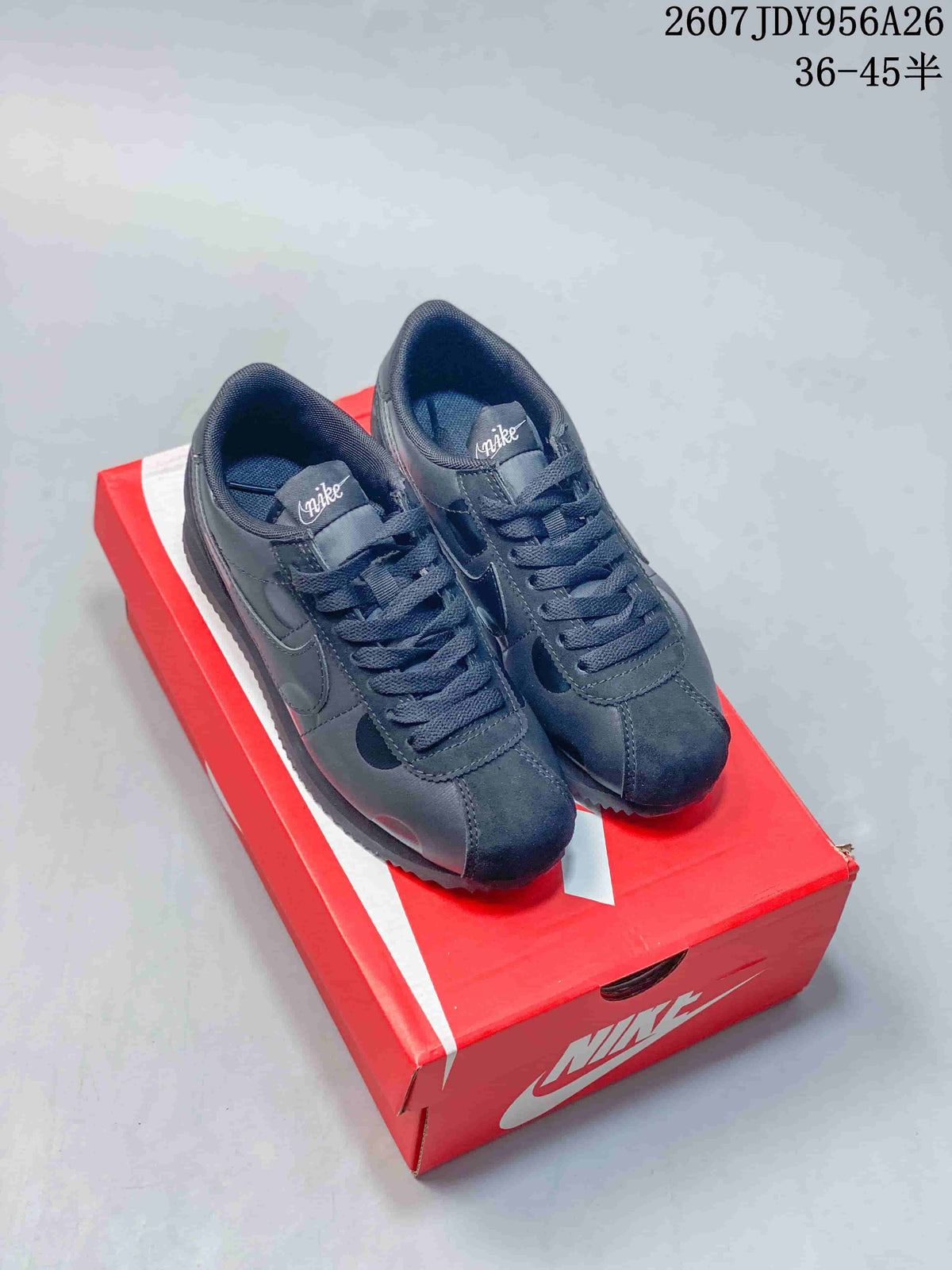 Pair of black Nike Classic Cortez sneakers displayed on a red Nike shoebox; image overlay shows 2607 JDY956A26 and sizes 36–45.
