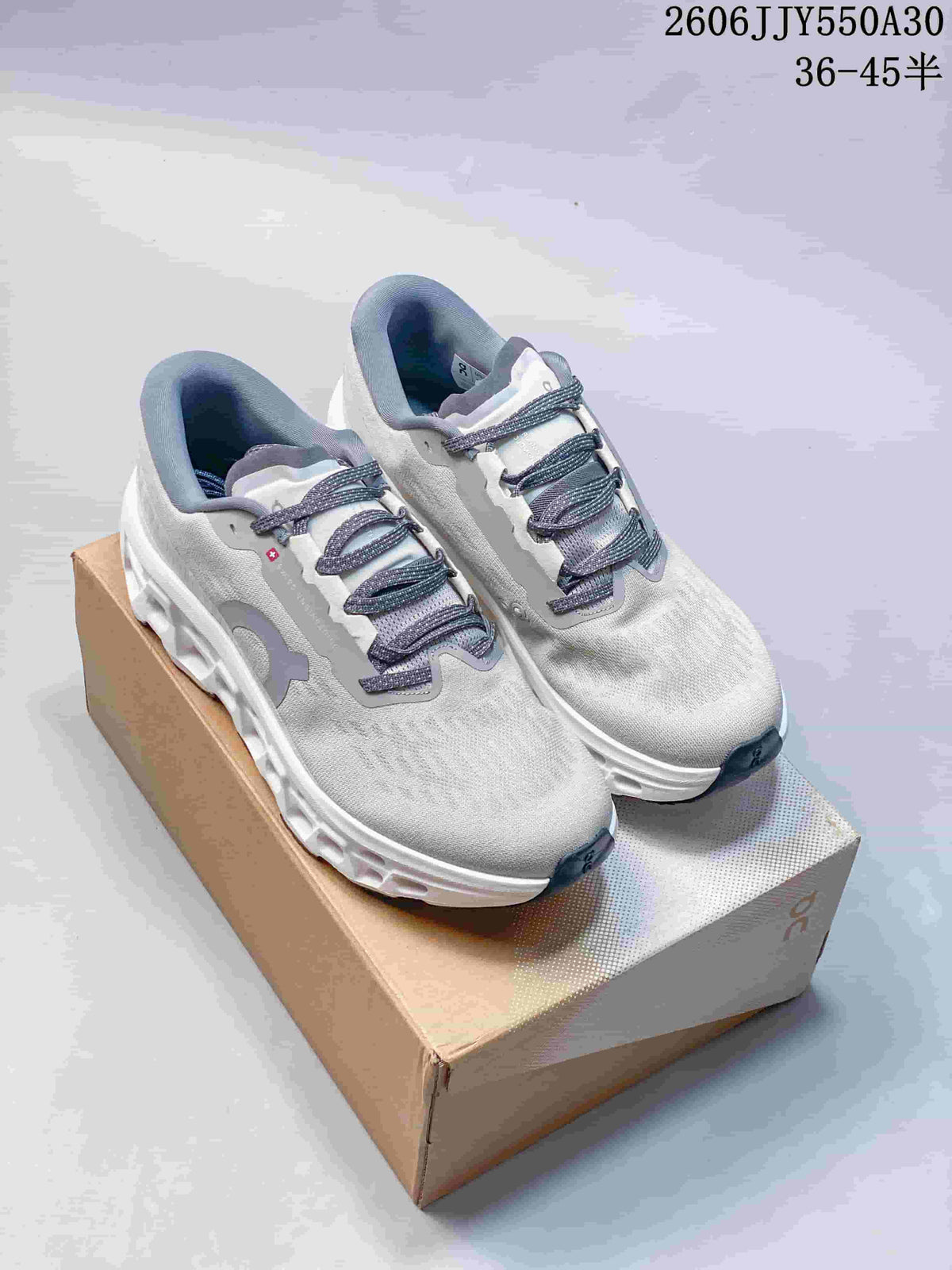 Pair of light gray On Cloudmonster 3 running shoes on a shoebox