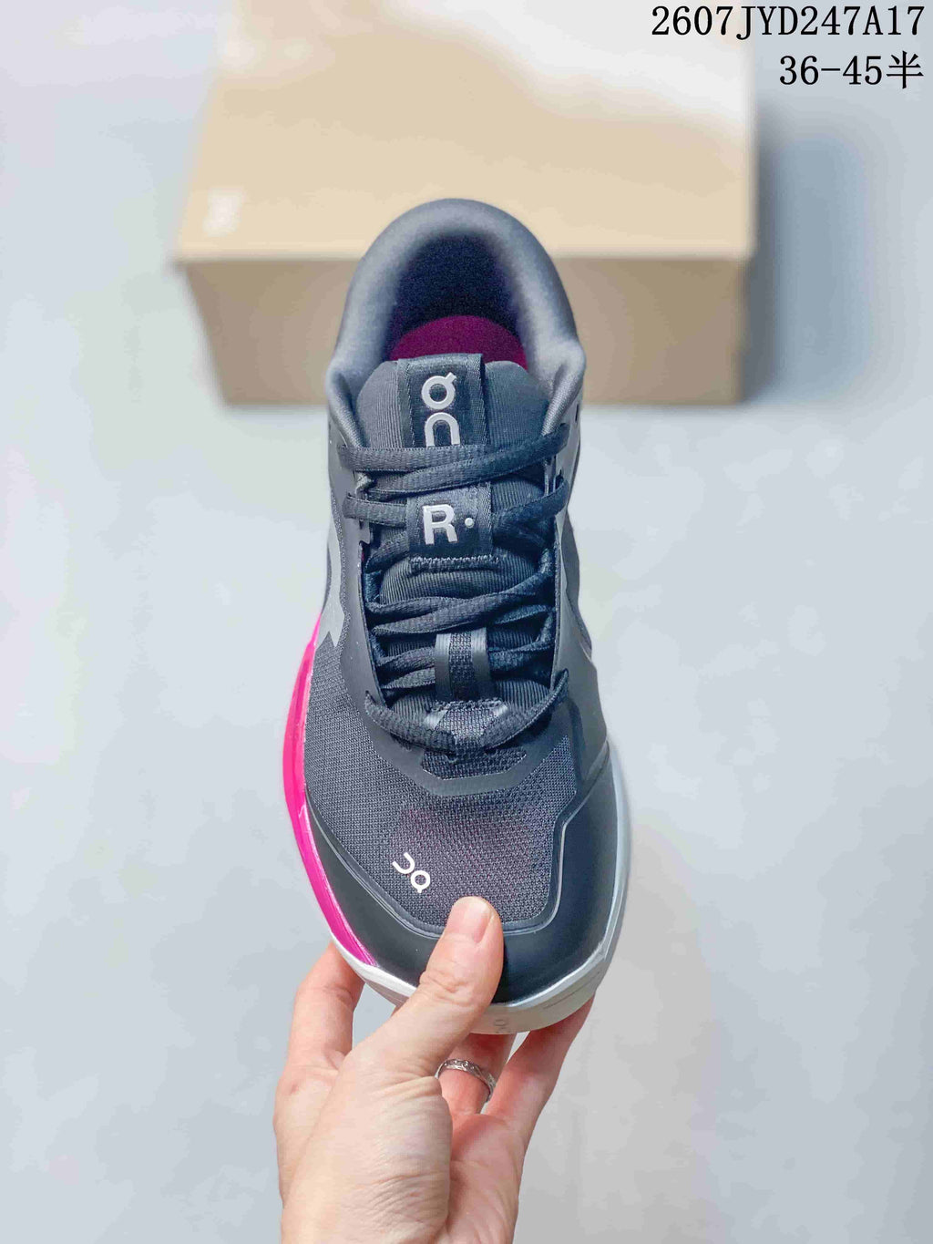 Front view of a dark gray lace-up sneaker with pink interior lining and contrasting tongue branding.