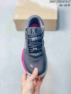 Front view of a dark gray lace-up sneaker with pink interior lining and contrasting tongue branding.