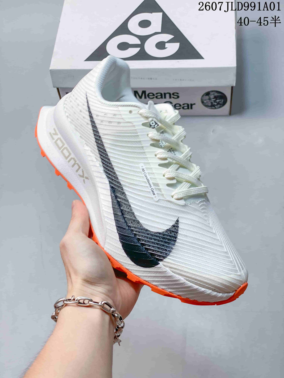 Side view of a white Nike ACG trail shoe with dark swoosh and orange outsole