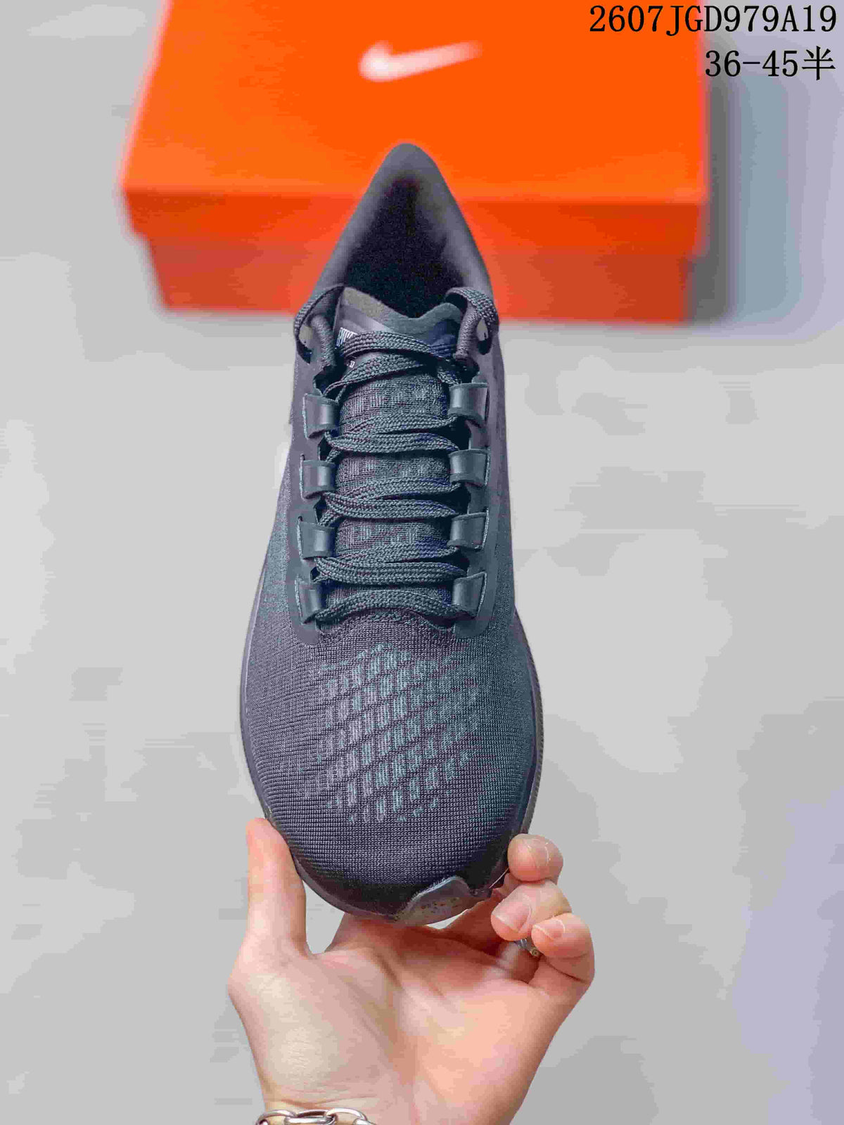 Top view of the dark lace-up sneaker showing the tongue, layered eyelets, and textured toe area.