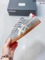 Side view of a gray low-top sneaker with cream side stripes, lace closure, and an amber-colored outsole; image text shows style code 2607LY976A26 and size range 40–45.