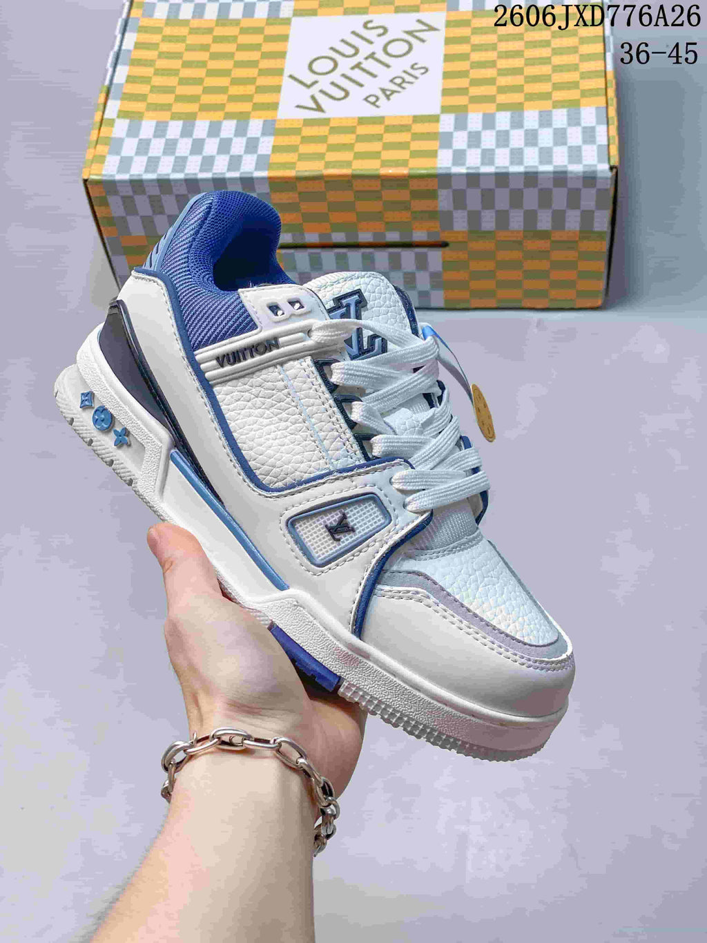 White low-top sneaker with blue accents, shown beside a patterned box