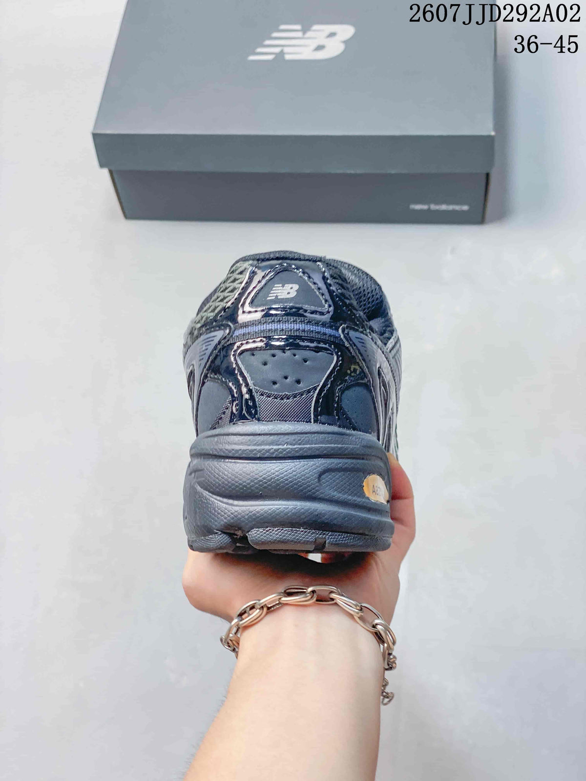 Rear view of the dark gray sneaker showing the padded heel, layered heel construction, and New Balance shoebox.