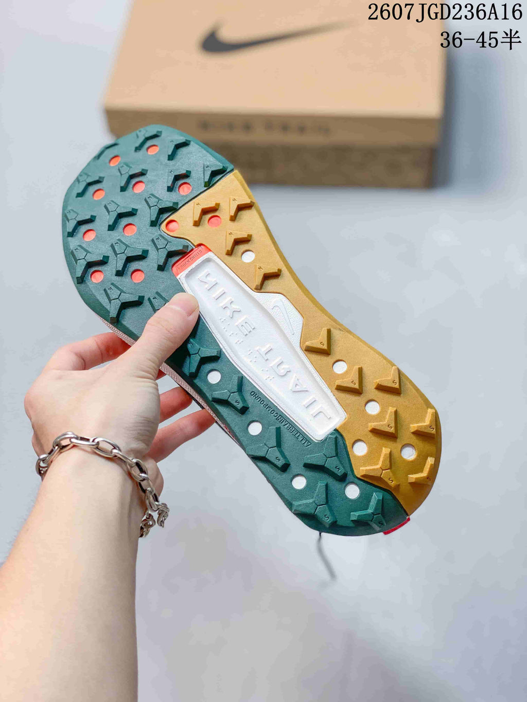 Close-up of the sneaker outsole showing a two-tone green and tan lugged tread with circular openings and ReactX branding.