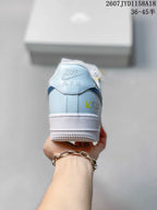 Rear view of a light blue and white sneaker showing the Nike Air tongue branding, heel stitching, and textured outsole.