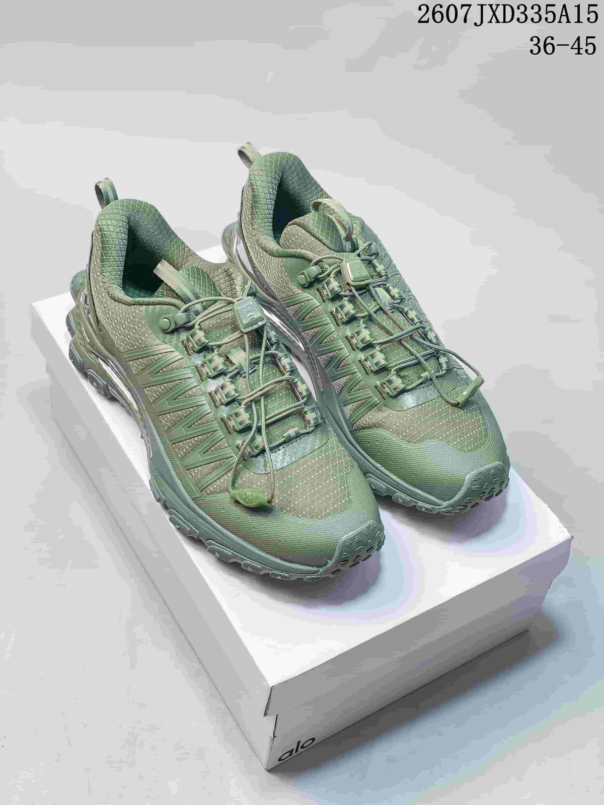 Pair of green Alo Runner Trail sneakers displayed on a shoebox, showing the low-top shape, quick-lacing system, and lugged outsole.