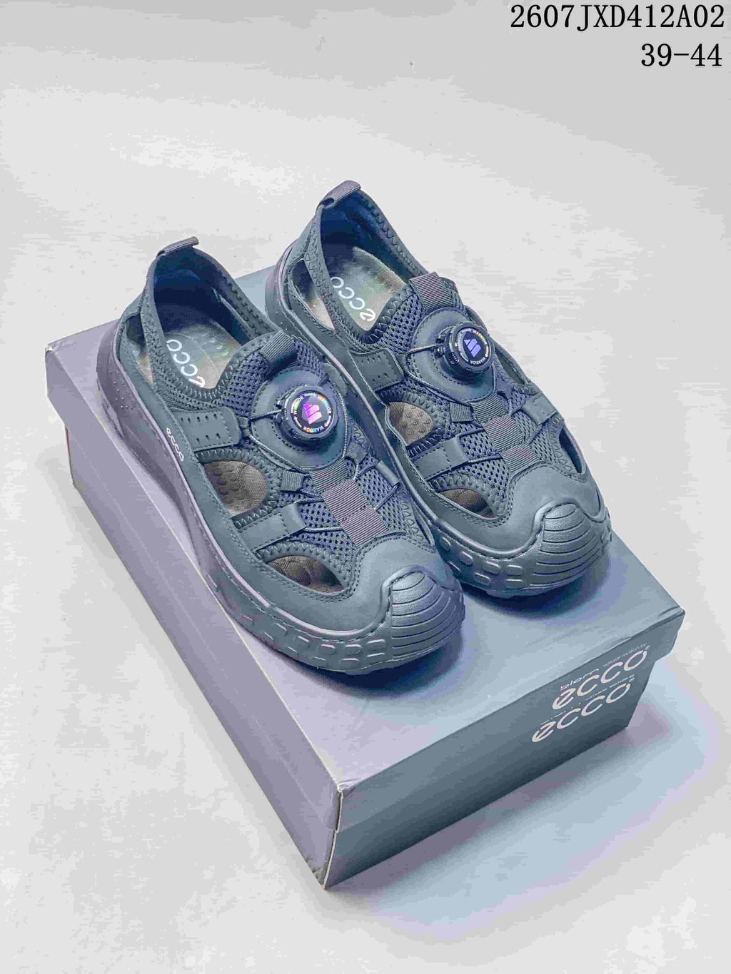 Pair of dark gray ECCO closed-toe sandals with dial-style closures, photographed on a shoebox.