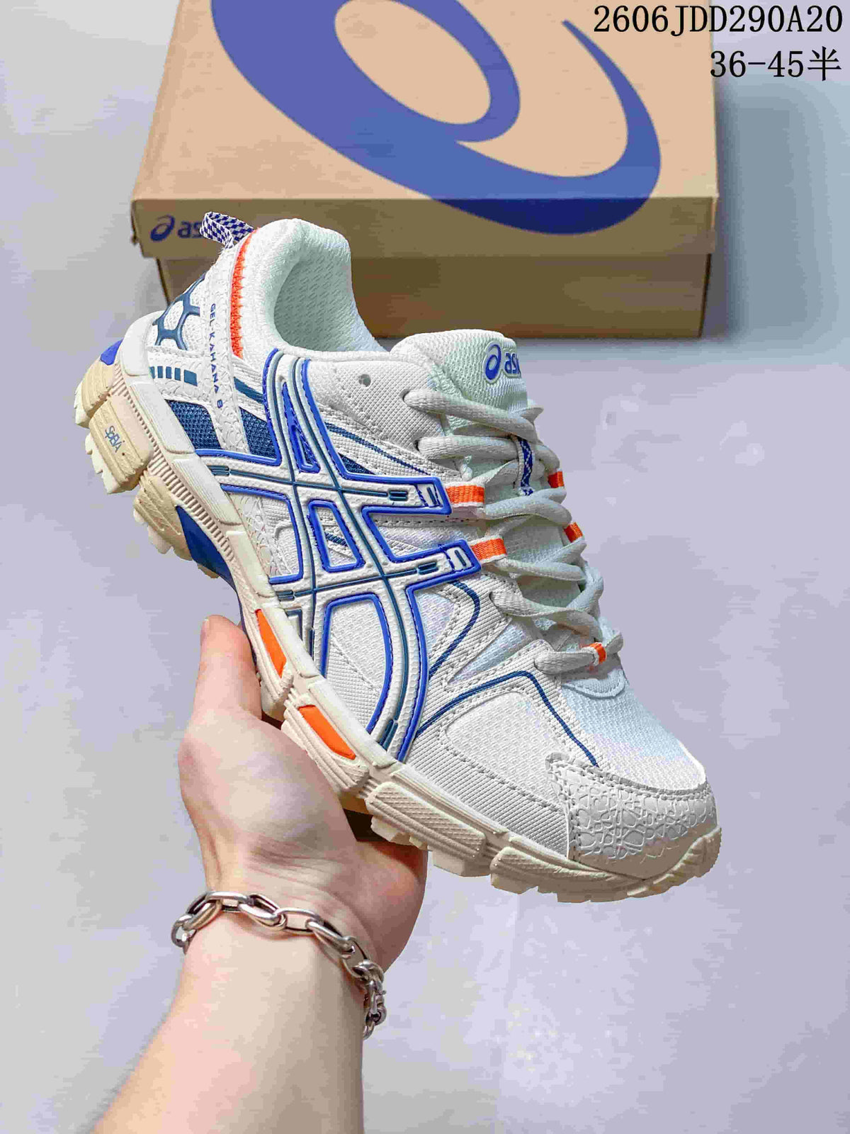 Angled side view of the white ASICS sneaker with blue overlays, orange accents, and a rugged outsole.