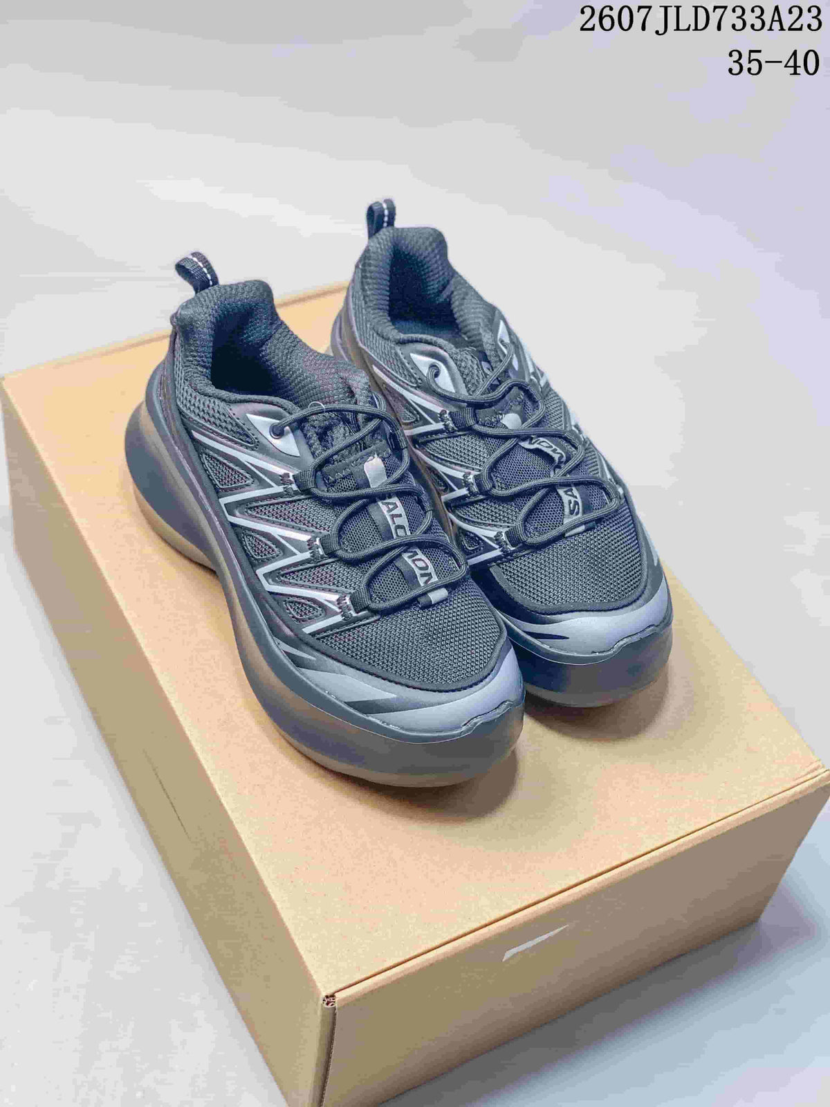 Pair of black and gray Comme des Garcons SHIRT x Salomon XT-6 sneakers displayed on a box, with the source size range 35–40 visible.