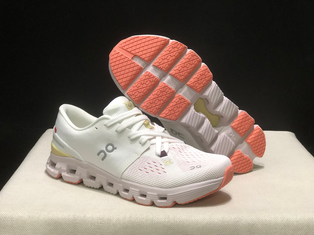 Angled view of the shoes with one outsole visible, showing coral traction sections and segmented construction.