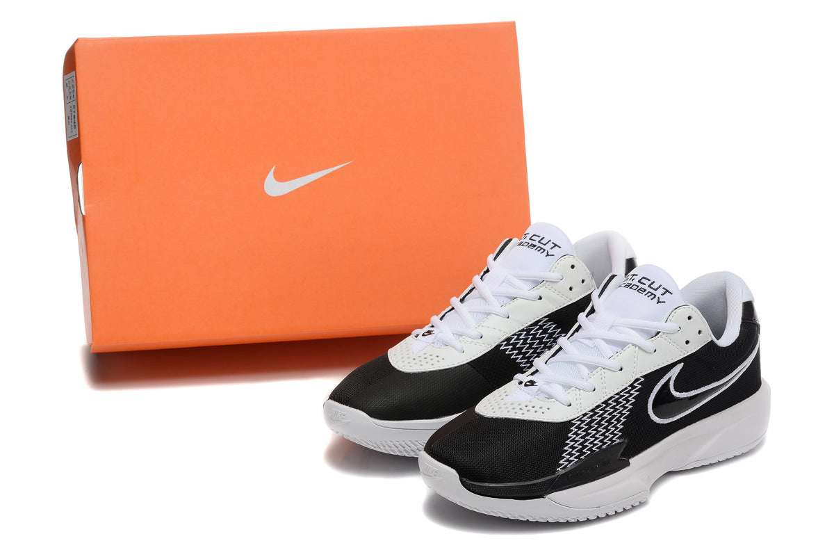 Black and white Nike G.T. Cut Academy shoes displayed beside an orange Nike shoe box.