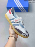 Angled side view showing the Samba marking, blue stripes, patterned toe panels, hook-and-loop strap, and gum-colored sole.