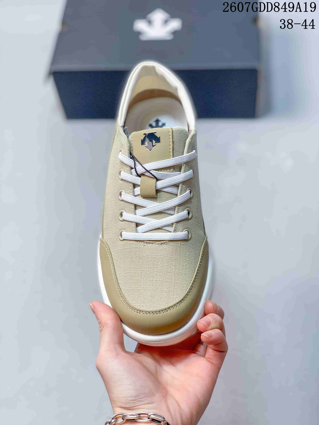 Top view of the beige lace-up sneaker showing the white laces, tongue branding, and contrasting toe panel.