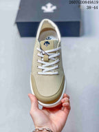 Top view of the beige lace-up sneaker showing the white laces, tongue branding, and contrasting toe panel.