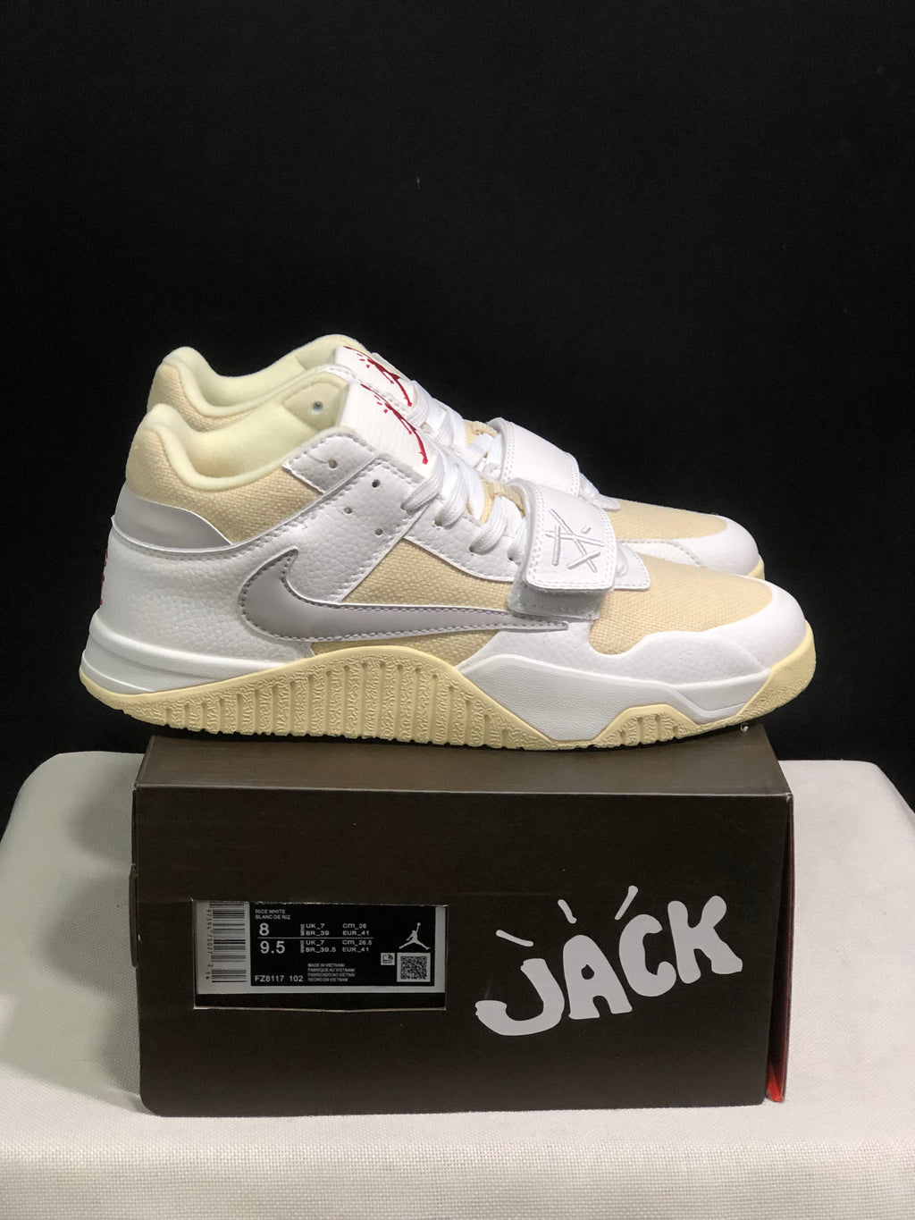 Pair of white and cream Jordan Jumpman Jack sneakers displayed on a black shoebox, with the box label visible.