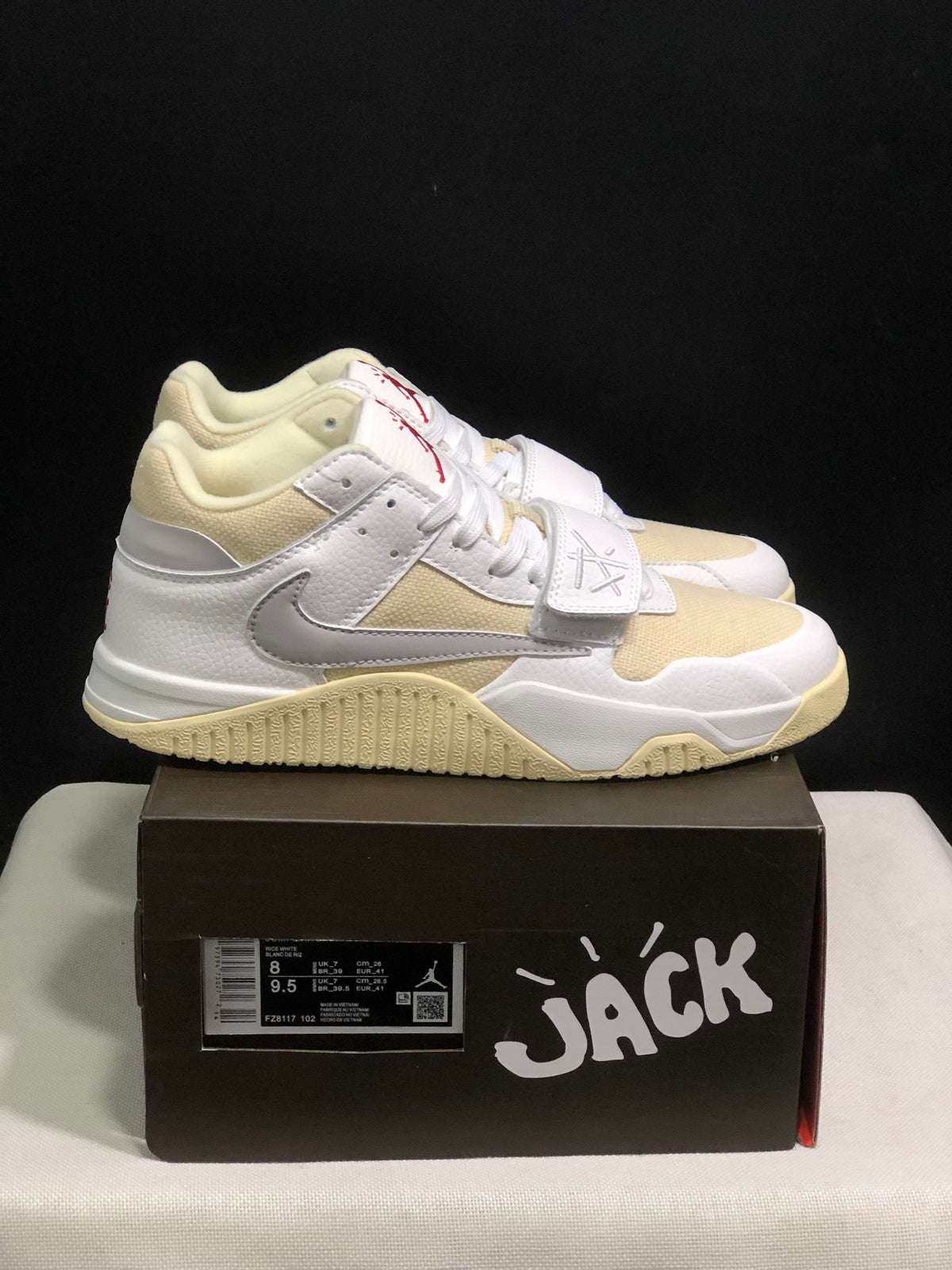 Pair of white and cream Jordan Jumpman Jack sneakers displayed on a black shoebox, with the box label visible.