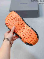 Close view of the orange outsole showing a raised tire-inspired tread pattern.