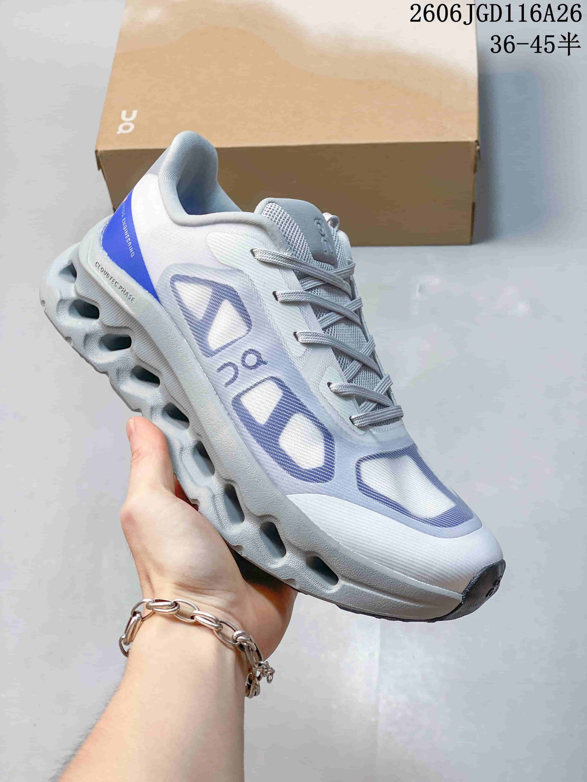 Side view of a white On Cloudtilt Remix sneaker with blue accents and a sculpted sole.