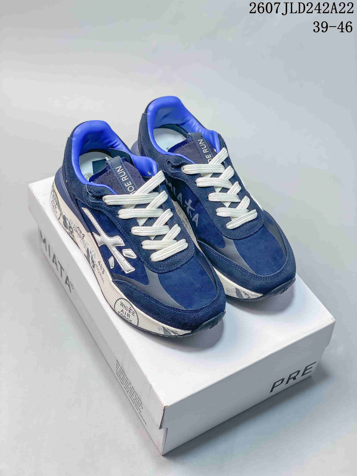 Navy blue Premiata Lander trainers displayed on a Premiata shoe box, showing white laces, blue lining and a white side logo.