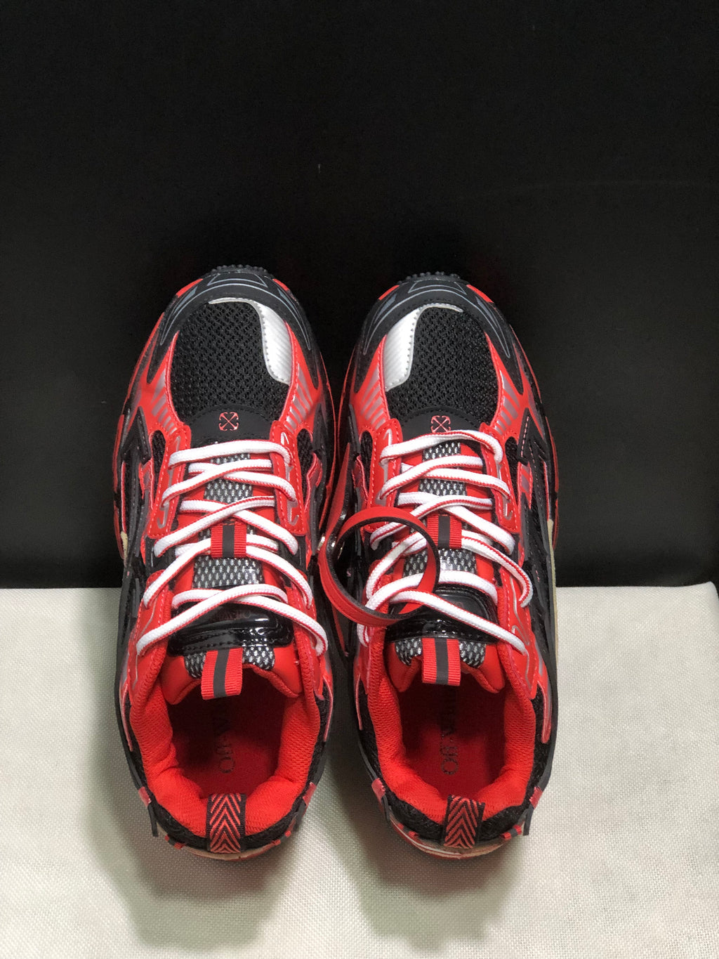 Top view showing the rounded toes, white laces, mesh tongues, and red-and-black upper detailing.