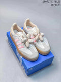 Pair of white and pink adidas Sambae sneakers with large flower lace decorations, shown on a blue adidas shoe box.