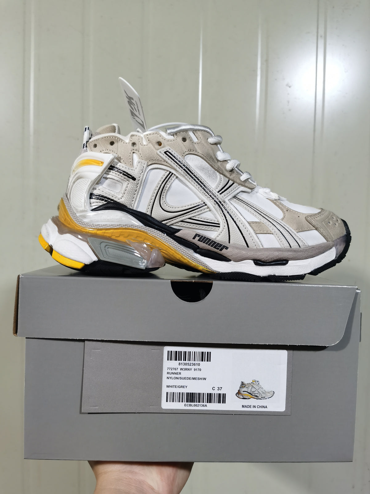 Puma Runner 9170 sneaker in white and grey with black detailing and yellow outsole accents, shown on its box.