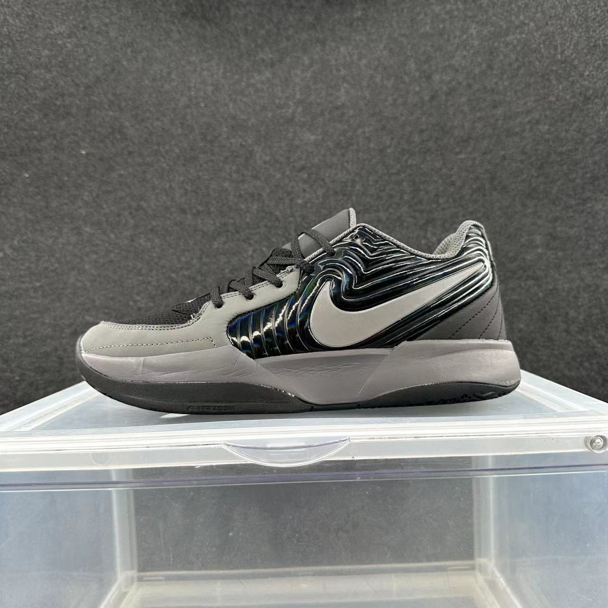 Side view of a black, gray, and silver Nike low-top sneaker with a large silver Swoosh and layered sole.