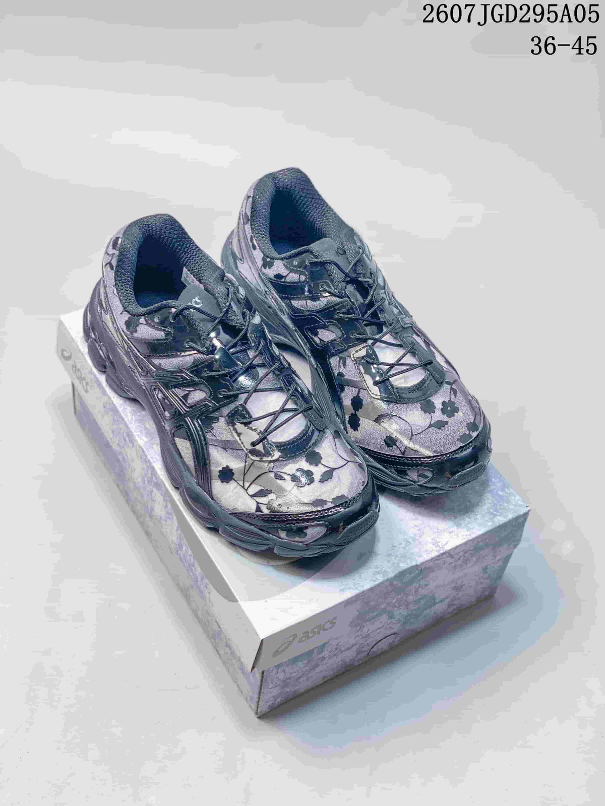Pair of dark gray and black floral ASICS sneakers displayed on a shoebox; image text shows style code 2607TGD295A05 and size range 36–45.