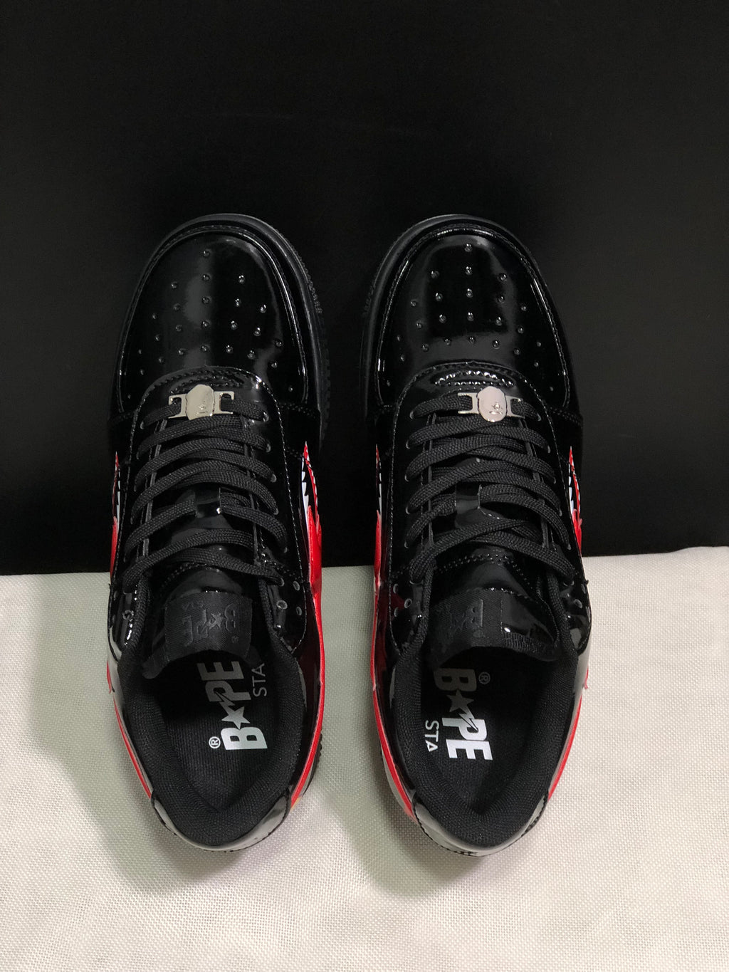 Top view showing black laces, perforated toe panels, padded collars, and BAPE STA branding inside the shoes.