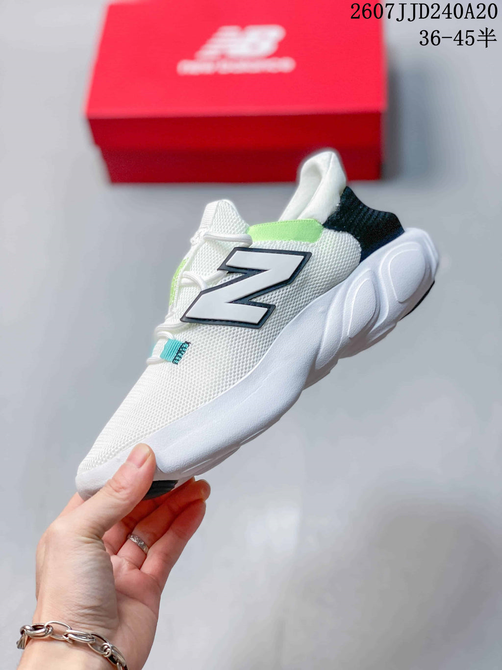 Side view of a white New Balance sneaker with a large black-edged N logo, light green accents, lace fastening and a sculpted white outsole.