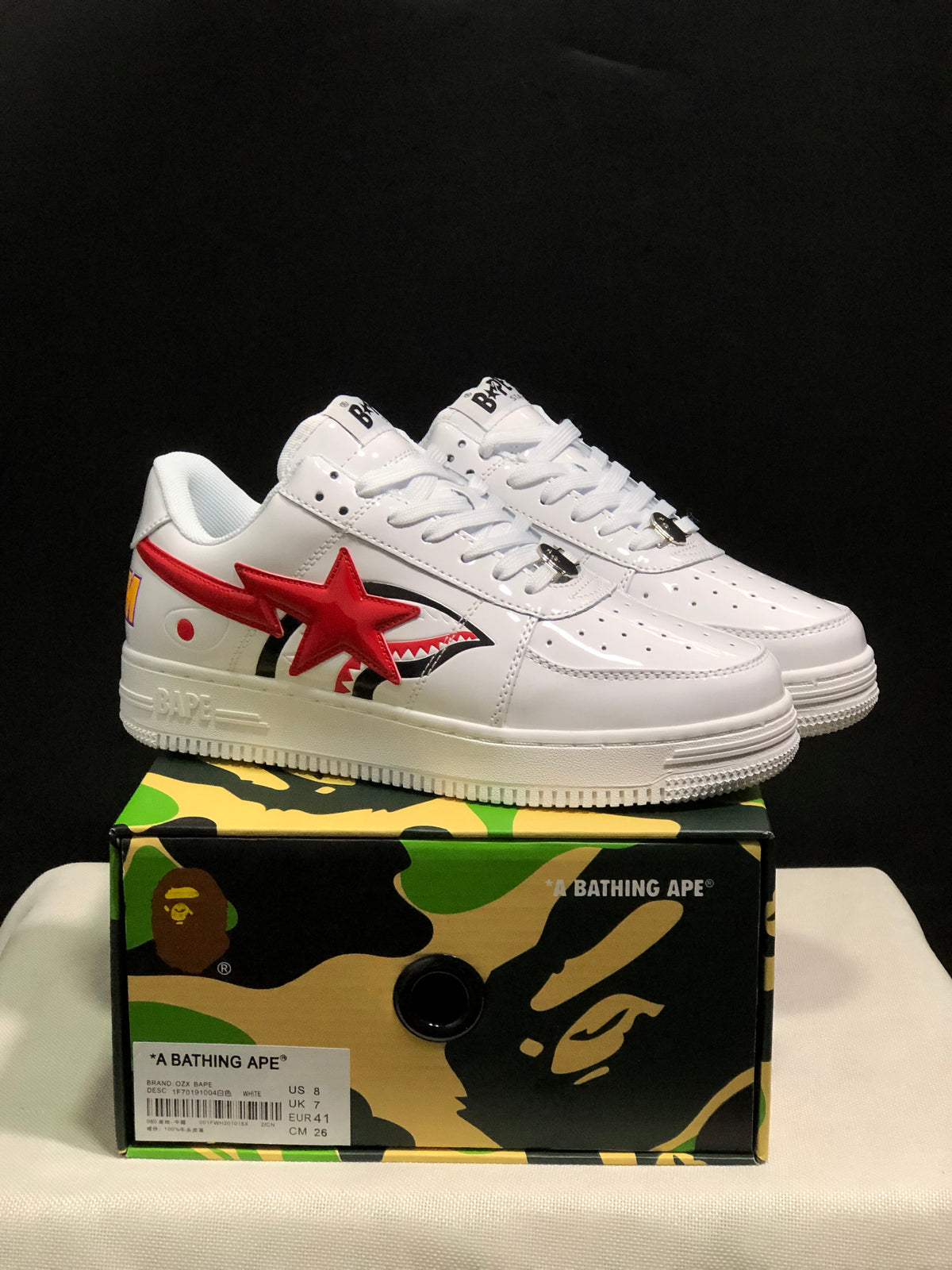 Pair of white and red BAPE low-top sneakers displayed on a camouflage BAPE shoebox; the box label shows EU 41, US 8, UK 7 and CM 26.
