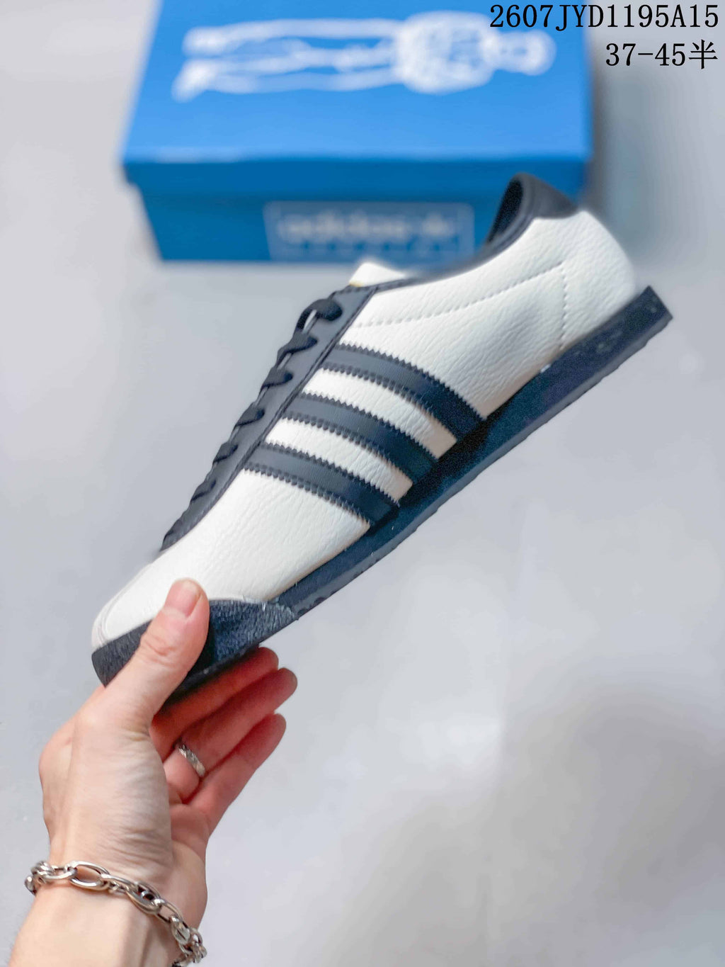Side profile showing the off-white upper, navy three stripes, and low-profile sole.