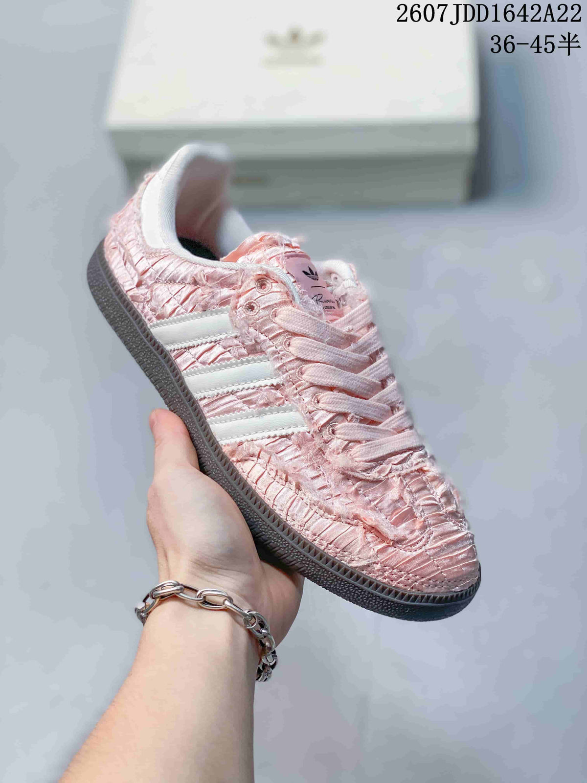 Close-up side view of a pink ruched adidas Samba OG sneaker with pale three-stripe branding.