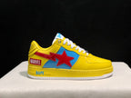 Outer side view of a yellow sneaker showing the red star, blue panel, Marvel patch, BAPE midsole branding, and white outsole.