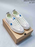 White and gray Descente low-top sneakers with a blue side emblem on a box