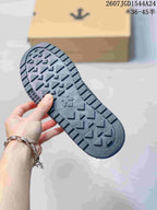 Black sneaker outsole shown from below, featuring a geometric tread pattern and a shoebox in the background.