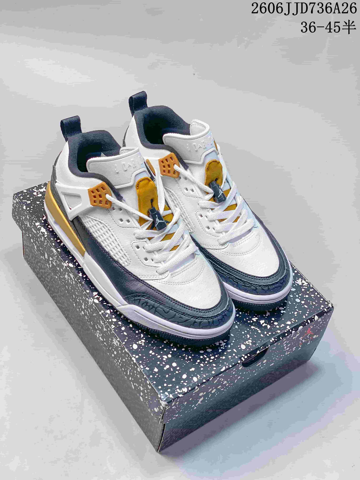 Pair of white, navy, and gold Jordan Spizike Low sneakers displayed on a speckled shoebox.